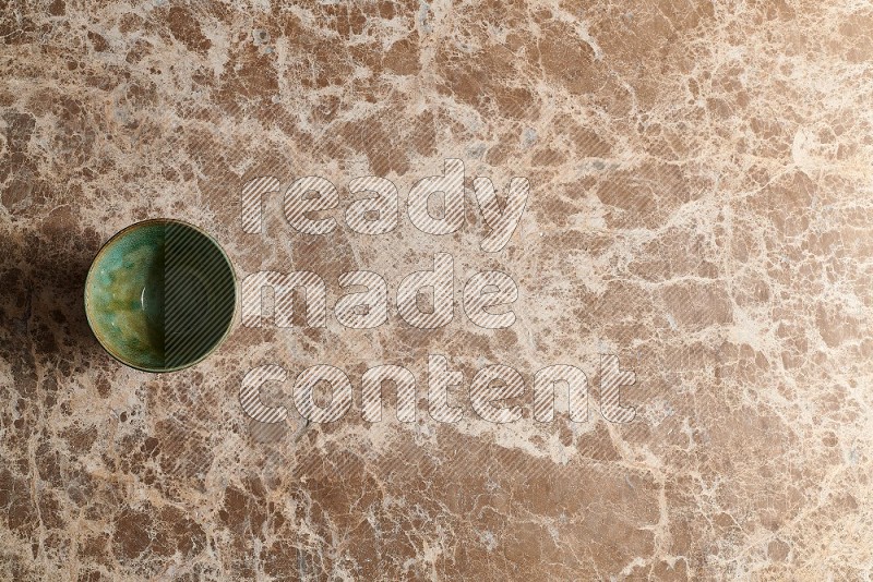 Top View Shot Of A Dark Green Pottery Bowl On beige Marble Flooring