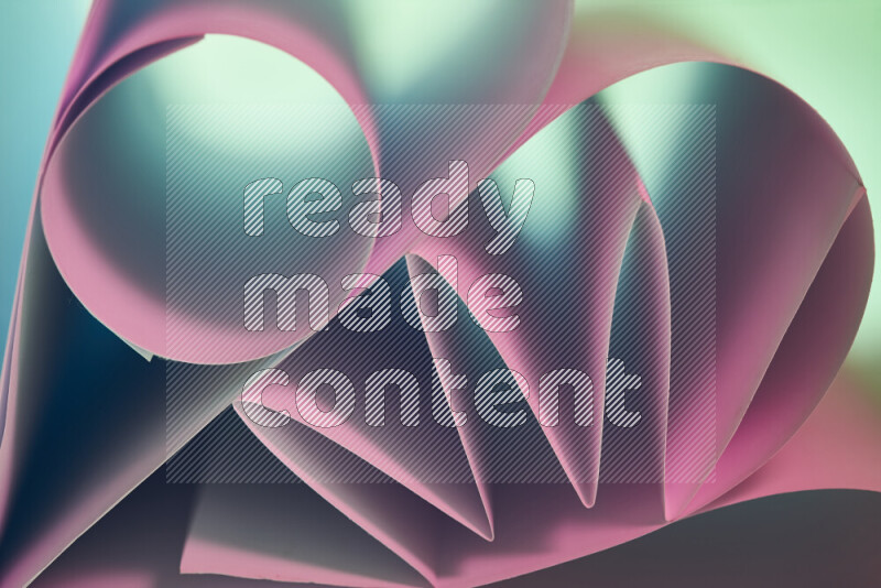 عرض فني لطيات الورق تخلق مزيج من الأشكال الهندسية، مضاءة بإضاءة ناعمة بدرجات اللون الأخضر والوردي