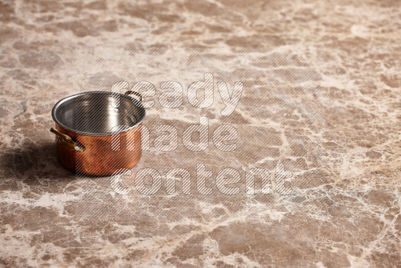 A small copper pot on beige marble background