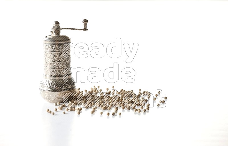White pepper beads with a metal grinder on white flooring