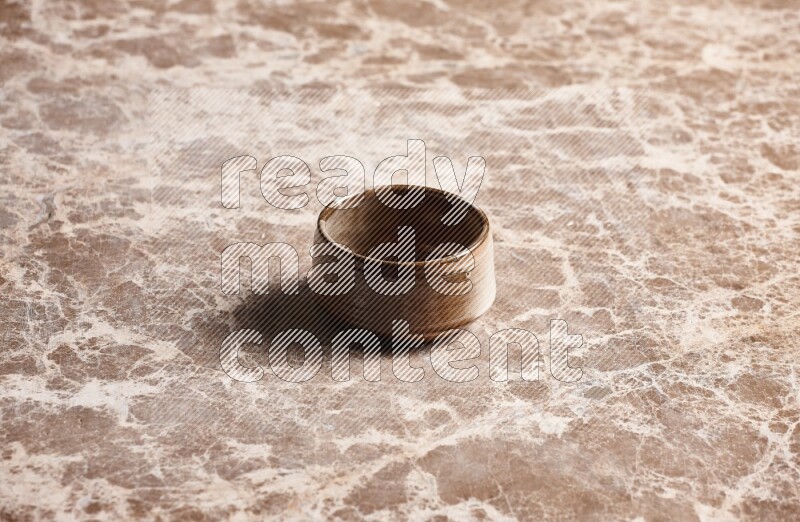 A brown pottery bowl on beige marble background