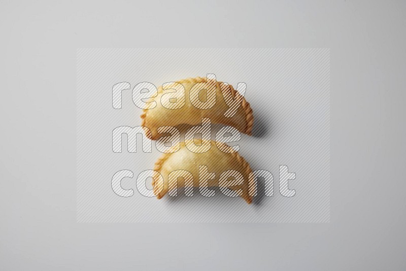 Two fried sambosa from a top angle on a white background