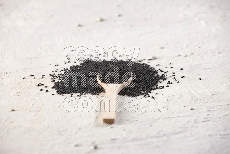 A wooden spoon full of black seeds on textured white flooring in different angles
