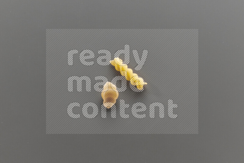 Snails pasta with other types of pasta on grey background