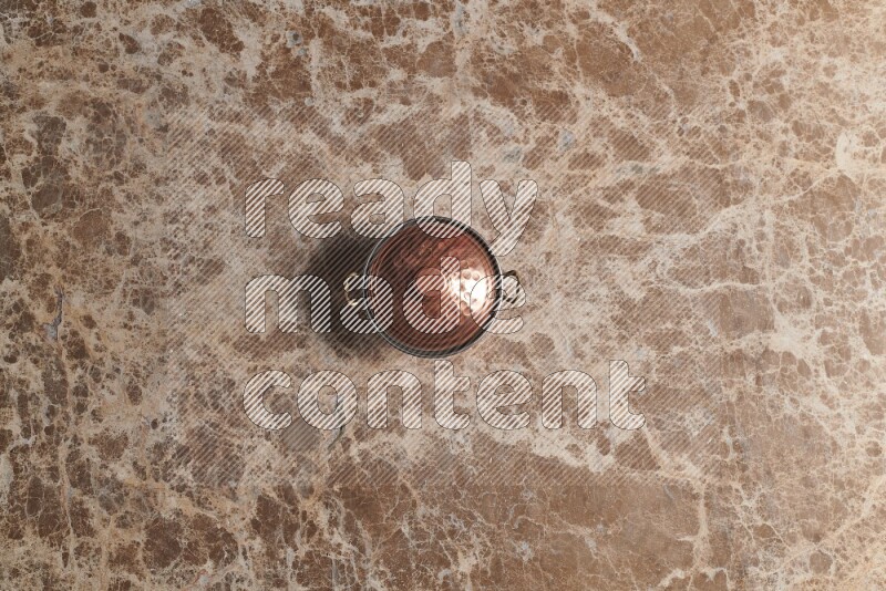 A small copper pot on beige marble background