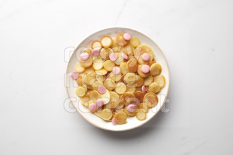 Top-view shot of pink chocolate chips cereal pancakes in a round bowl on white background