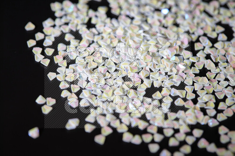 قطع صغيرة بلاستيكية ملونة للزينة متناثرة على خلفية سوداء