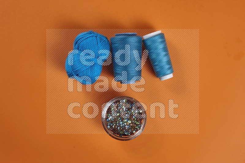 Blue sewing supplies on orange background