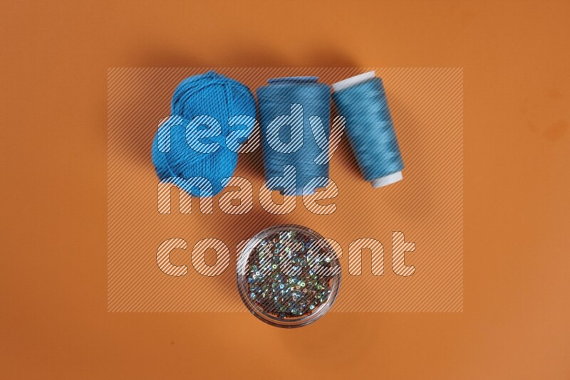 A blue collection of sewing and tailoring tools arranged on a orange background