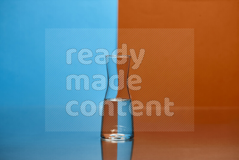 The image features a clear glassware filled with water, set against blue and dark orange background