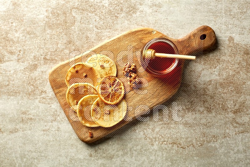 Five stacked dried orange mini pancakes on a wooden board on beige background