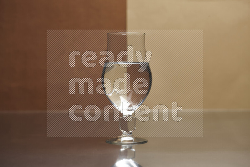 The image features a clear glassware filled with water, set against brown and beige background