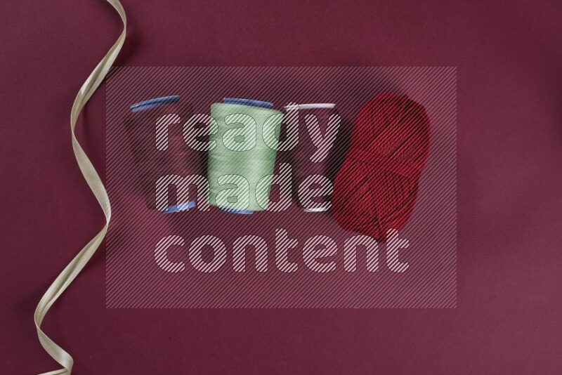 A green and red collection of sewing and tailoring tools arranged on a red background