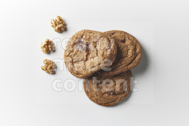 Chocolate chips cookies with walnuts beside it on a white background