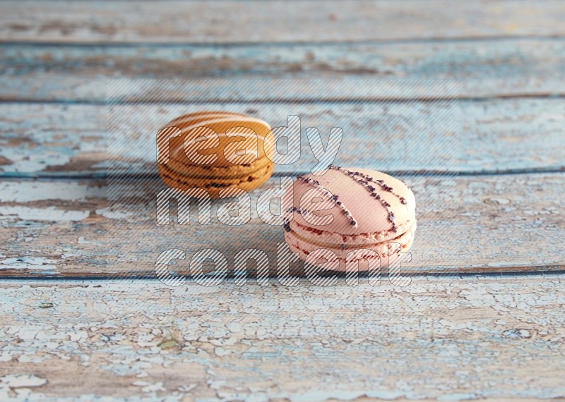 45º Shot of of two assorted Brown Irish Cream, and pink orange blossom  macarons on light blue background