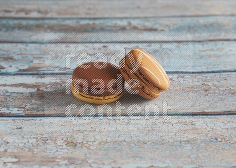 45º Shot of of two assorted Brown Irish Cream, and Yellow, and Brown Chai Latte macarons  on light blue background