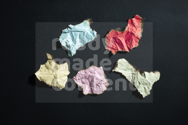 Burnt multicolored paper on black background