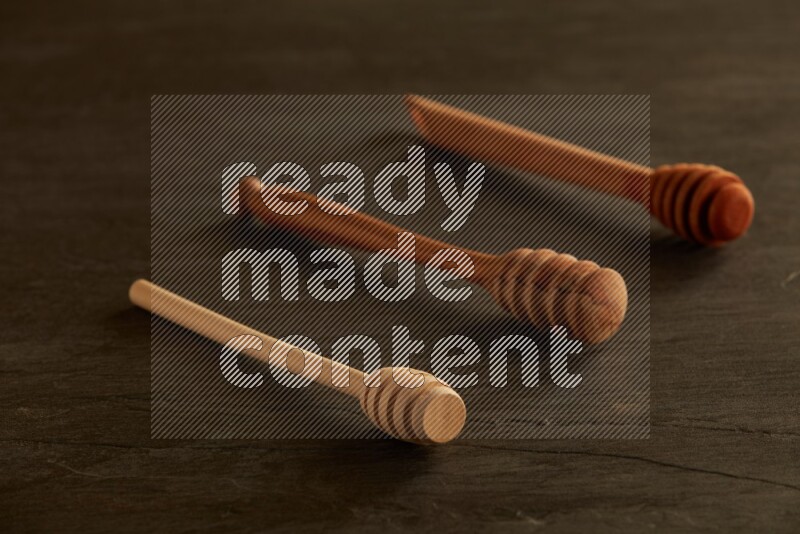 Wooden honey dipper on black slate background