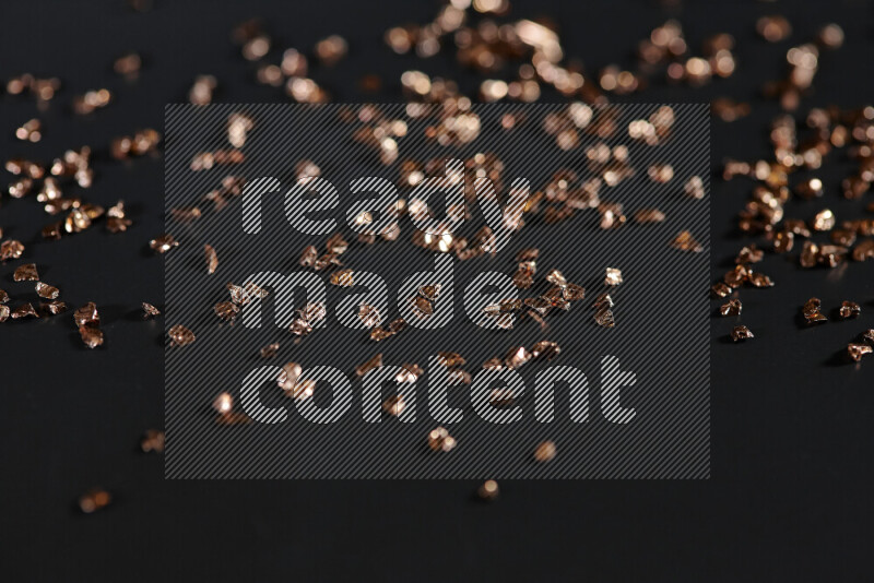 Bronze shimmering fragments of glass scattered on a black background