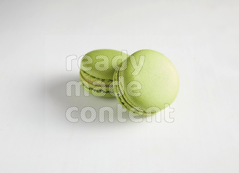 45º Shot of two Green Pistachio macarons on white background