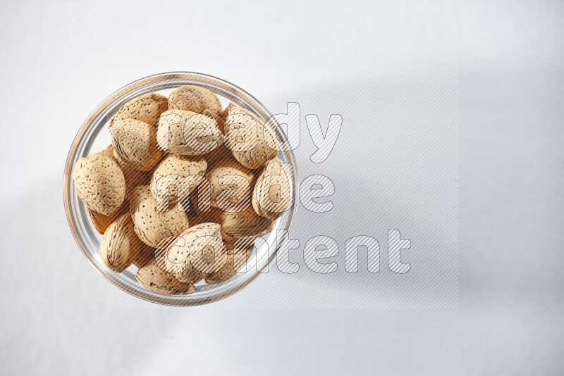 A glass bowl full of almonds on a white background in different angles