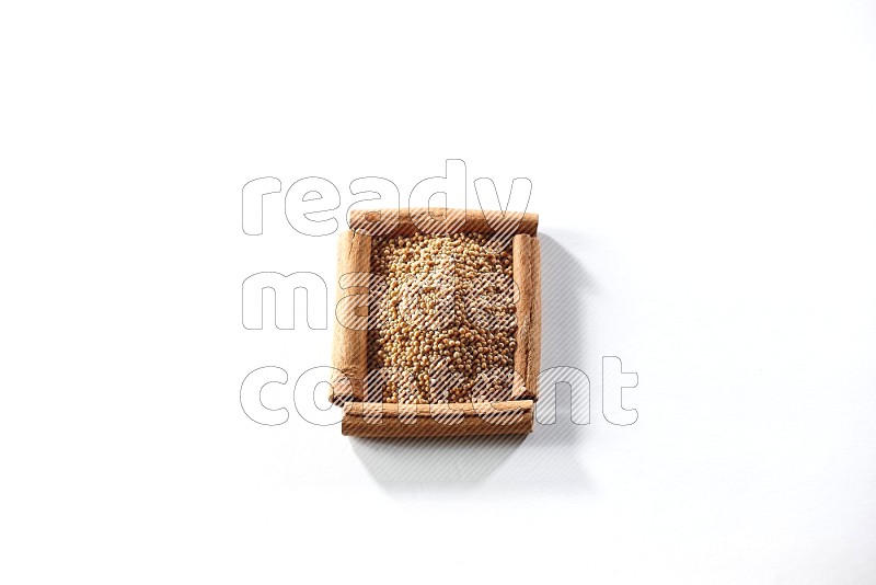 A single square of cinnamon sticks full of mustard seeds on white flooring
