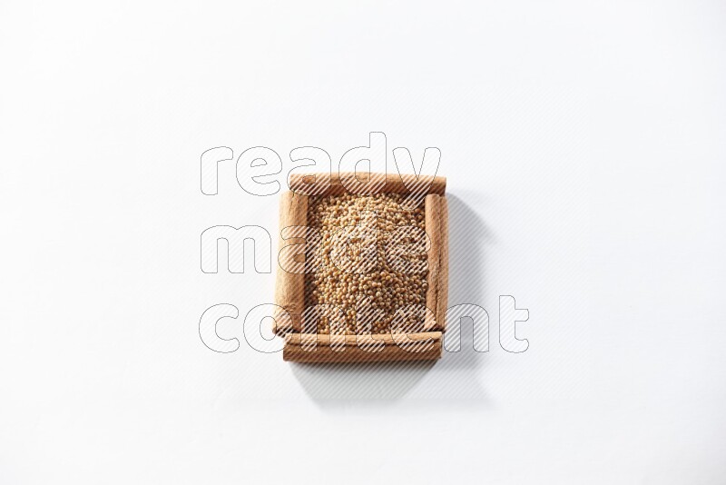 A single square of cinnamon sticks full of mustard seeds on white flooring