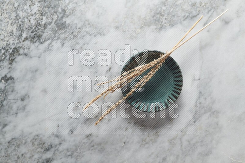 Wheat stalks on multicolored pottery plate on grey marble background
