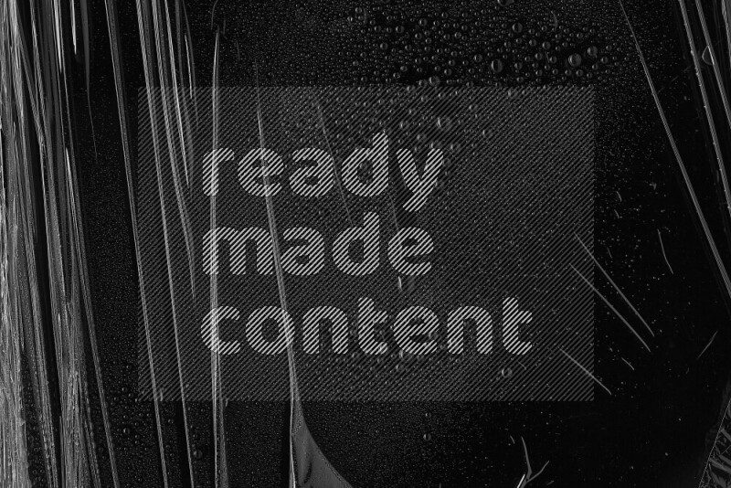 Plastic wrap with water drops on dark background