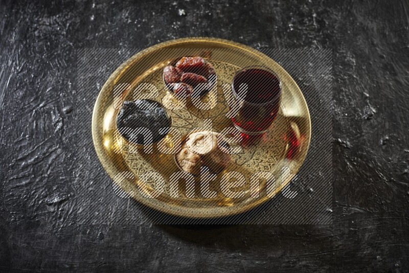 Dried fruits in metal bowls with tamarind on a tray in dark setup
