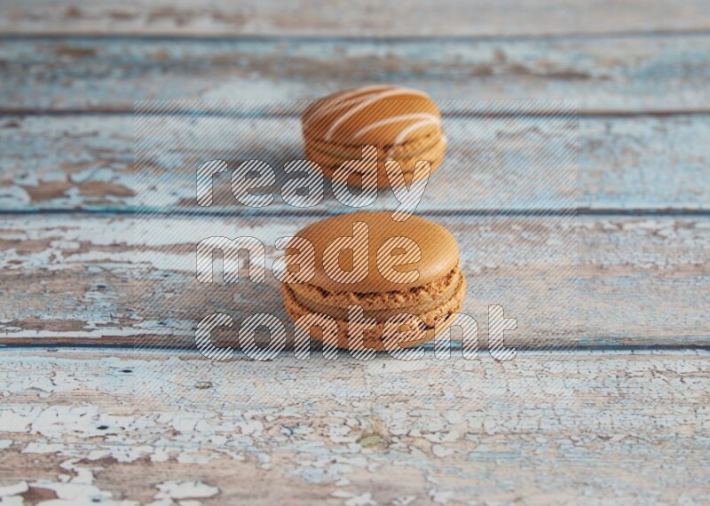 45º Shot of of two assorted Brown Irish Cream, and Brown Maple Taffy macarons  on light blue background