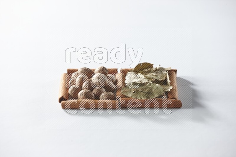 2 squares of cinnamon sticks full of bay laurel leaves and nutmegs on white flooring