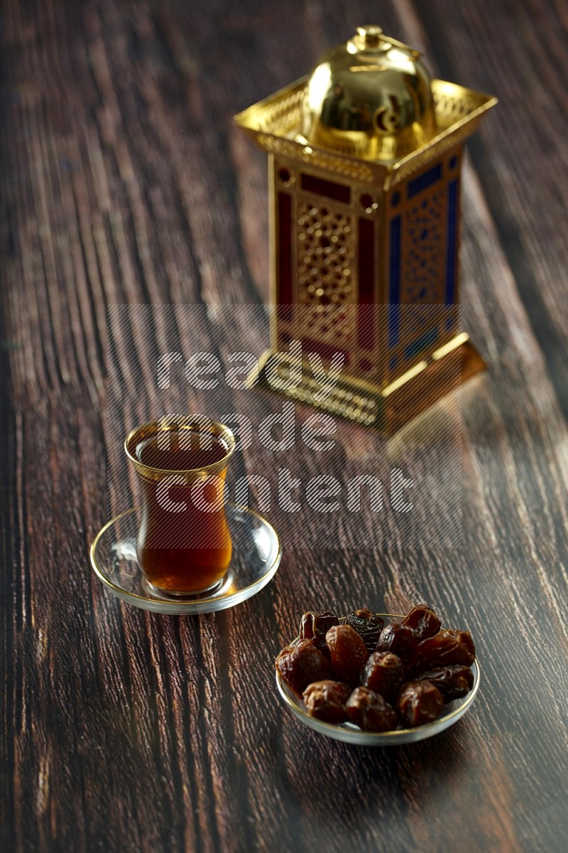 A golden lantern with different drinks, dates, nuts, prayer beads and quran on brown wooden background