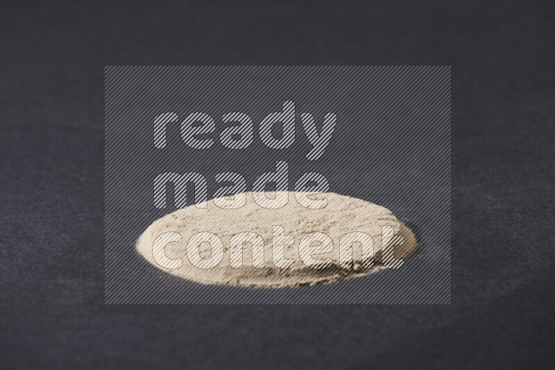 كومة من بودرة الثوم في شكل دائري علي خلفية سوداء