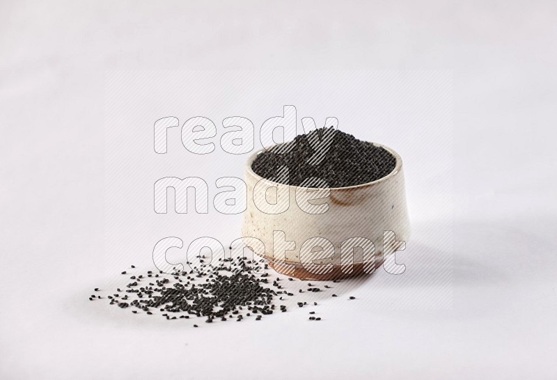 A beige pottery bowl full of black seeds and more seeds spread on a white flooring in different angles