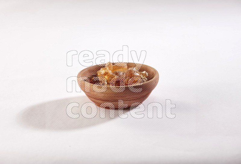 A wooden bowl full of gum arabic on a white flooring