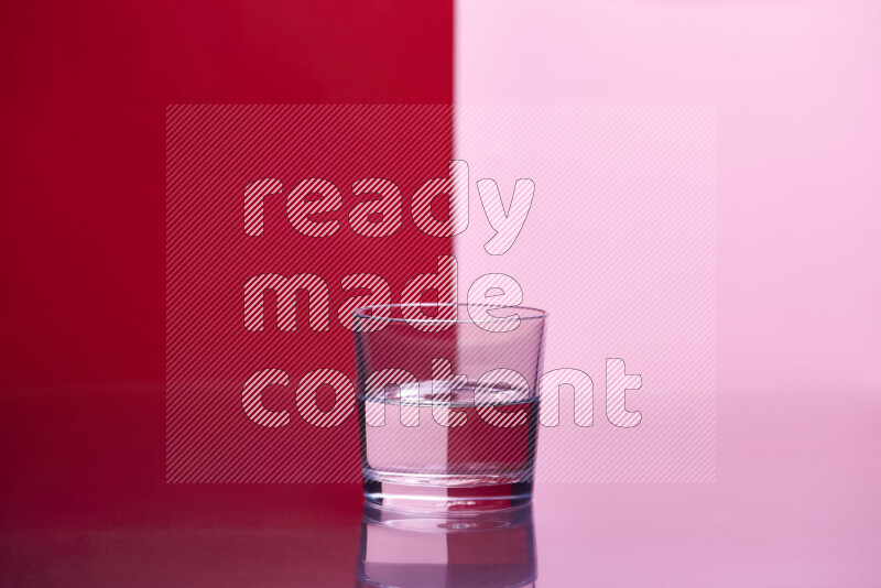 The image features a clear glassware filled with water, set against red and rose background