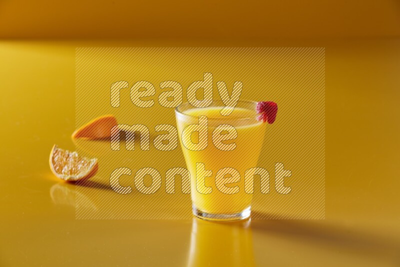 glass of orange juice with berry on yellow background