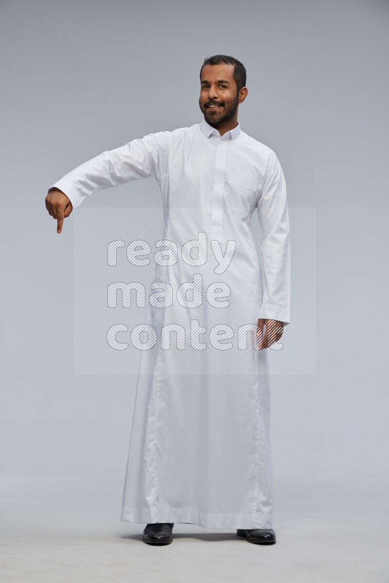 Saudi man Wearing Thob standing interacting with the camera on Gray background