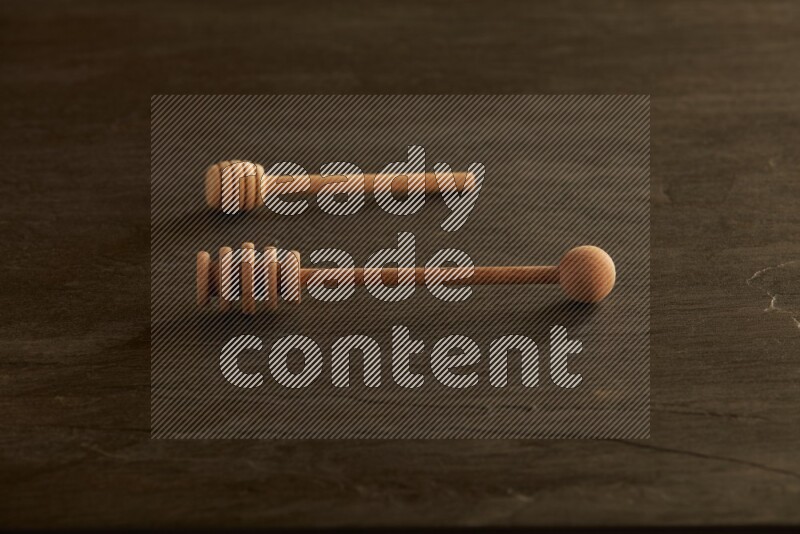 Wooden honey dipper on black slate background