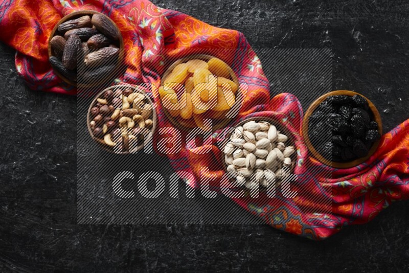 Dried fruits and nuts in wooden bowls in a dark setup