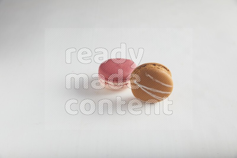 45º Shot of of two assorted Brown Irish Cream, and Pink Litchi Raspberry macarons on white background