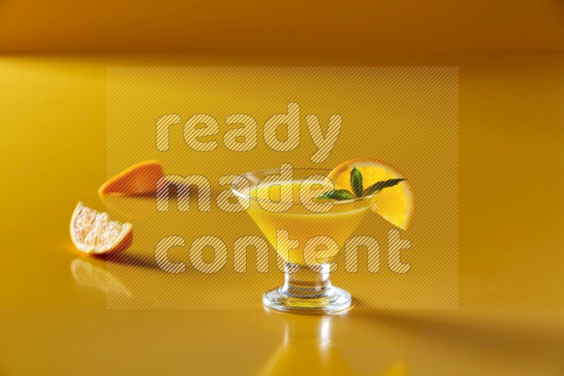 glass of orange juice with orange & mint  on yellow background