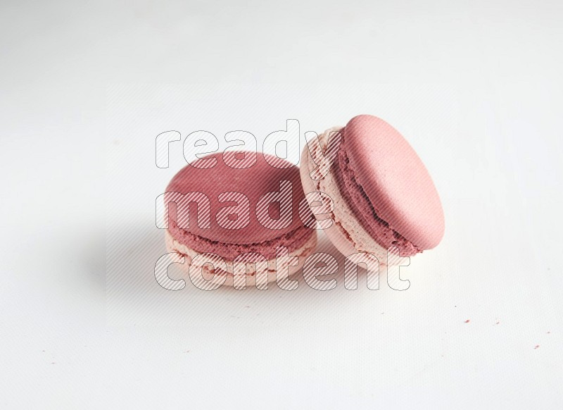 45º Shot of two Pink Litchi Raspberry macarons on white background