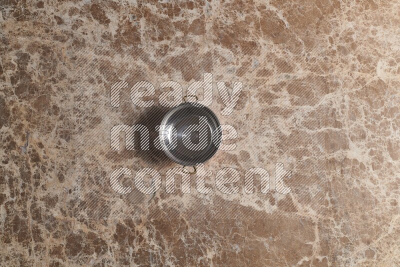 A small copper pot on beige marble background