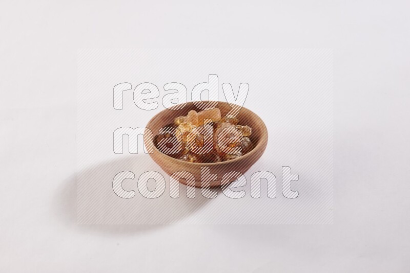 A wooden bowl full of gum arabic on a white flooring