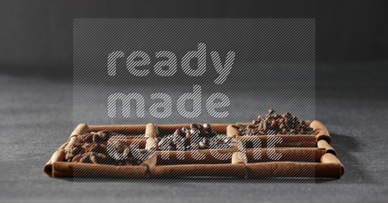 9 مربعات من أعواد القرفة ممتلئة بحبوب القهوة في المنتصف محاطة بجوزة الطيب والنعناع المجفف والقرنفل والريحان المجفف والزنجبيل المجفف والقرفة واليانسون والهيل على أرضية سوداء