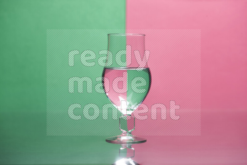 The image features a clear glassware filled with water, set against green and pink background