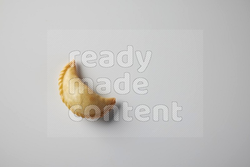 One fried sambosa from a top angle on a white background