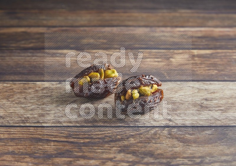 two pistachio stuffed madjoul date on a wooden background